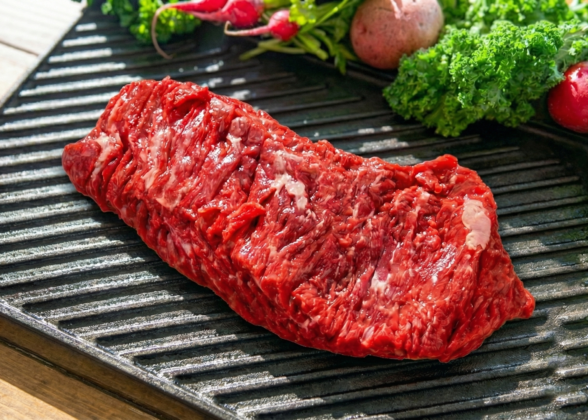 Beef Flap Steak on a grill pan with vegetables on a wooden surface
