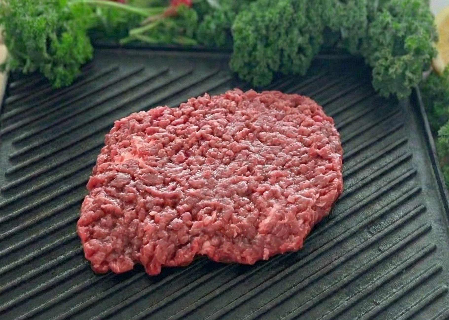 Beef Minute Steaks on a grill pan with vegetables and a lemon on a wooden surface