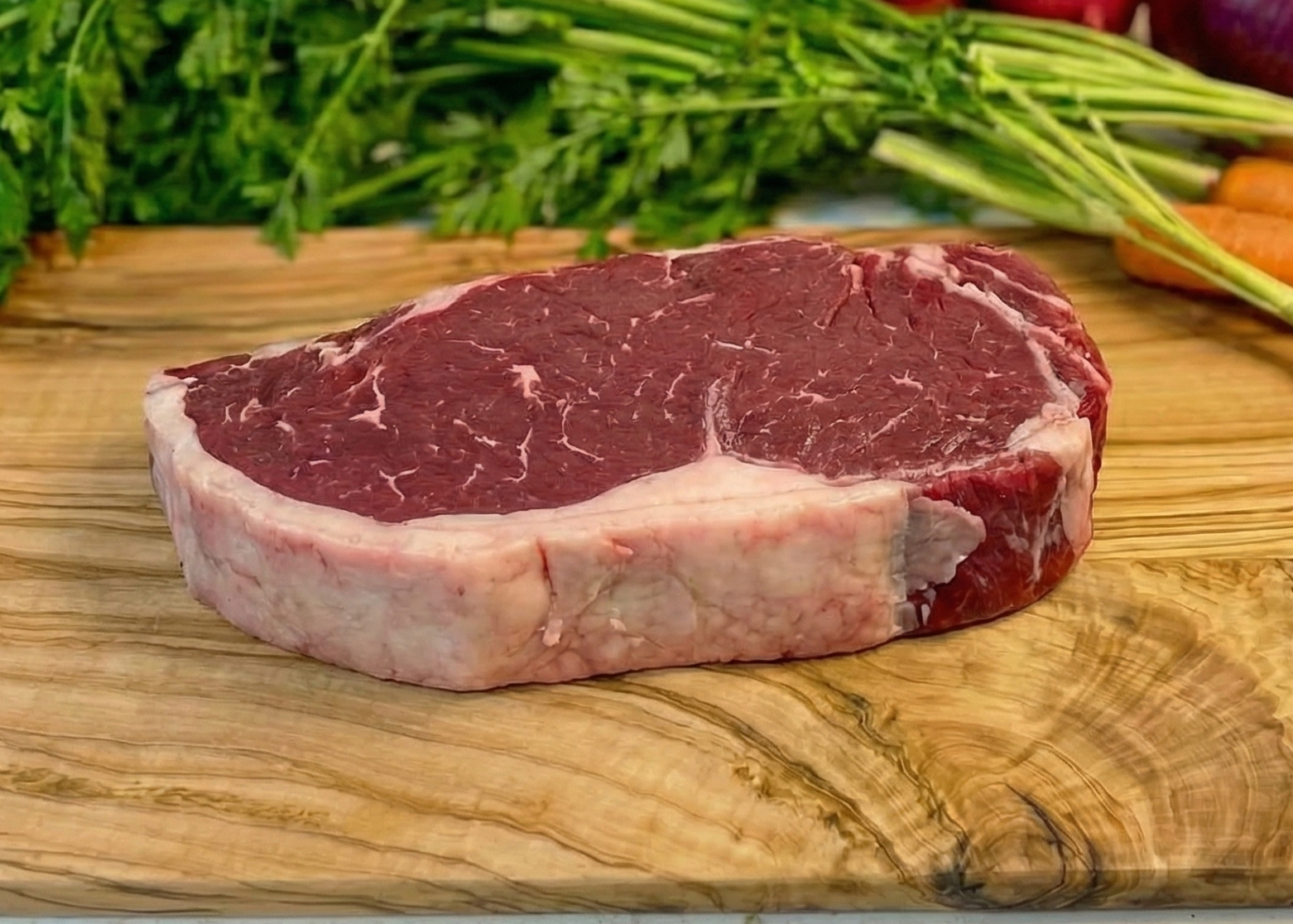 Beef Top Round Roast on a wooden cutting board with vegetables on a light background