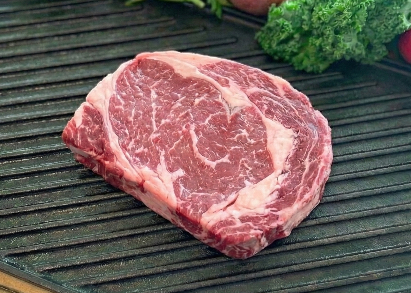 Boneless Buffalo Ribeye on a grill pan with vegetables on a wooden surface