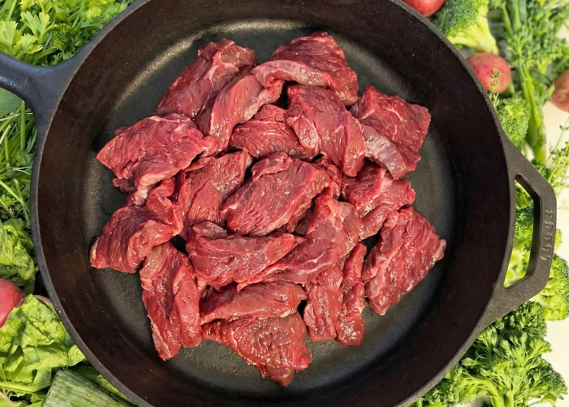 Buffalo Sirloin Stir Fry Strips in a cast iron skillet surrounded by fresh vegetables