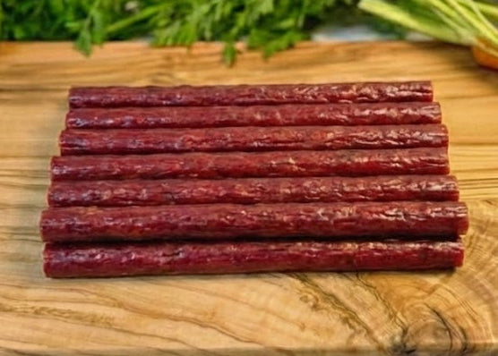 Buffalo Sticks on a wooden cutting board with vegetables in the background
