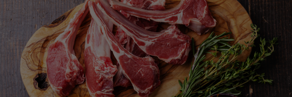 Raw lamb chops on a wooden board with herbs