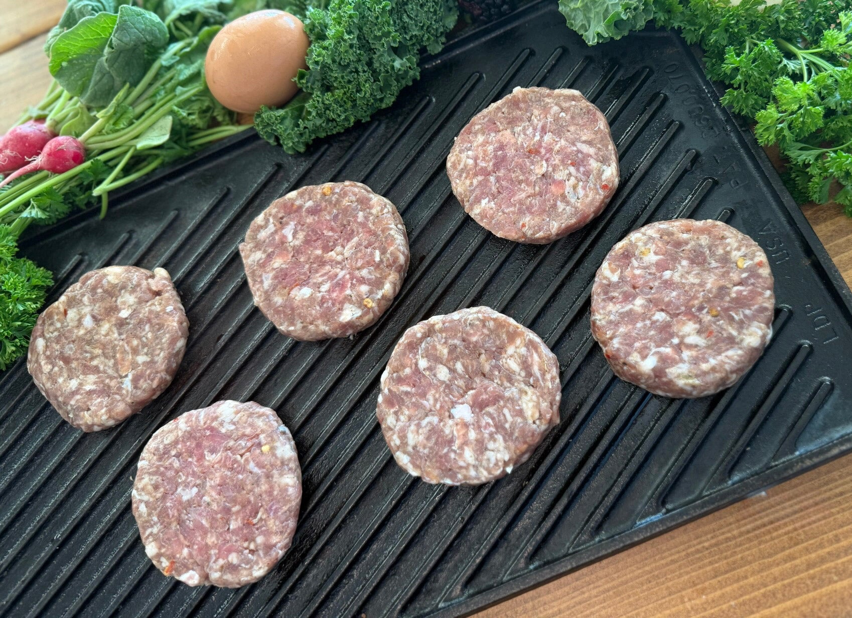 Raw chicken sausage on a grill pan with vegetables in the background