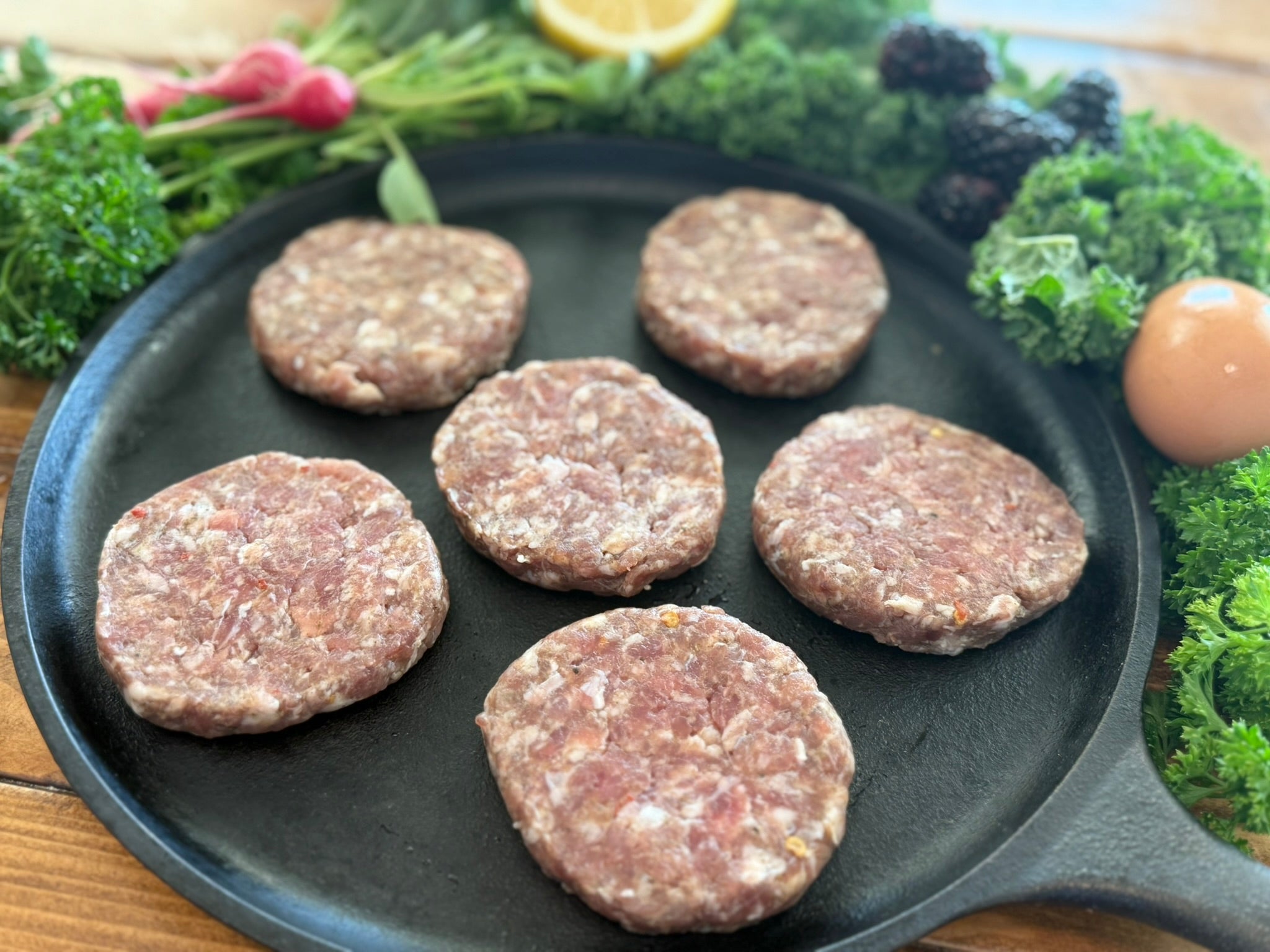Raw sausage patties on a cast iron skillet 