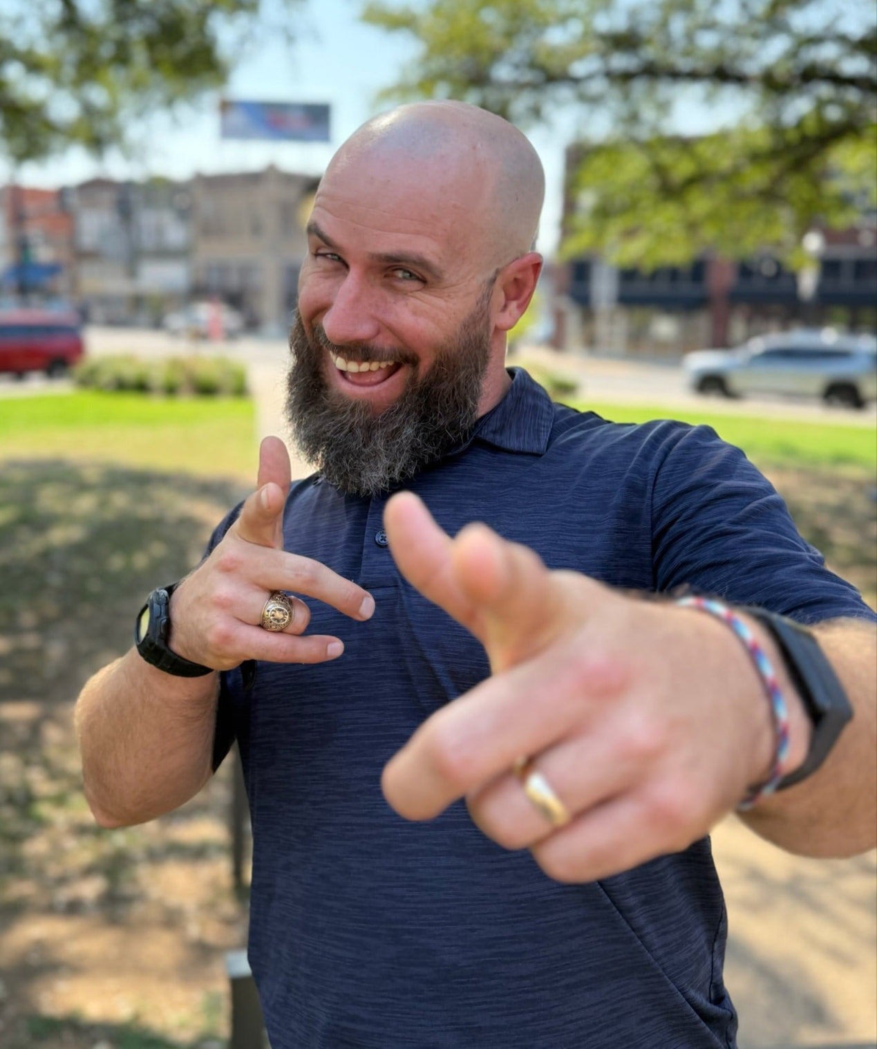 Man with a beard and blue shirt outdoors on a sunny day