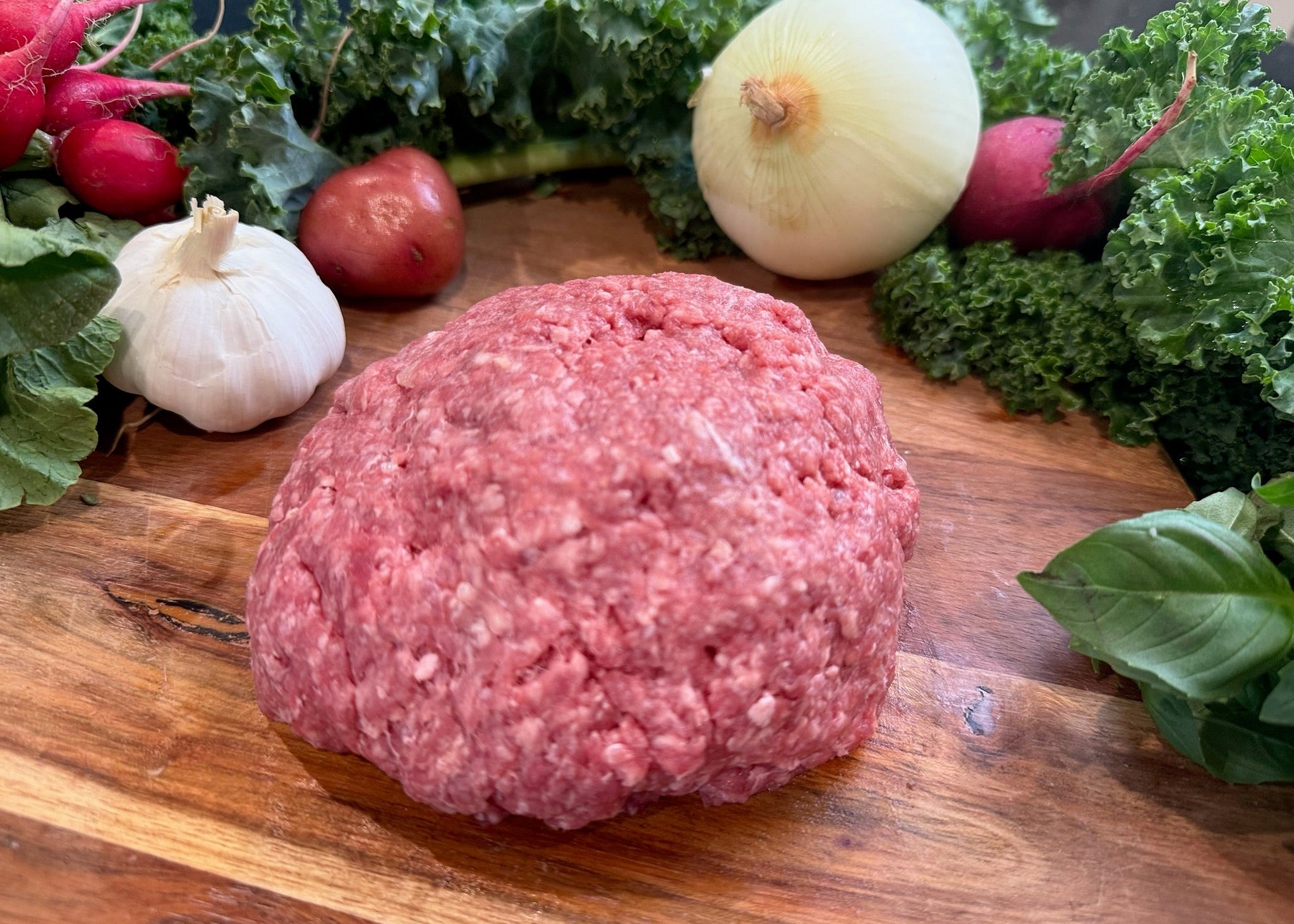 Patty of premium grass-fed ground beef on a wood cutting board