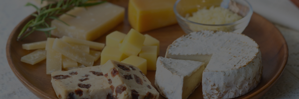 Assorted types of cheese on a wooden board with a white napkin.