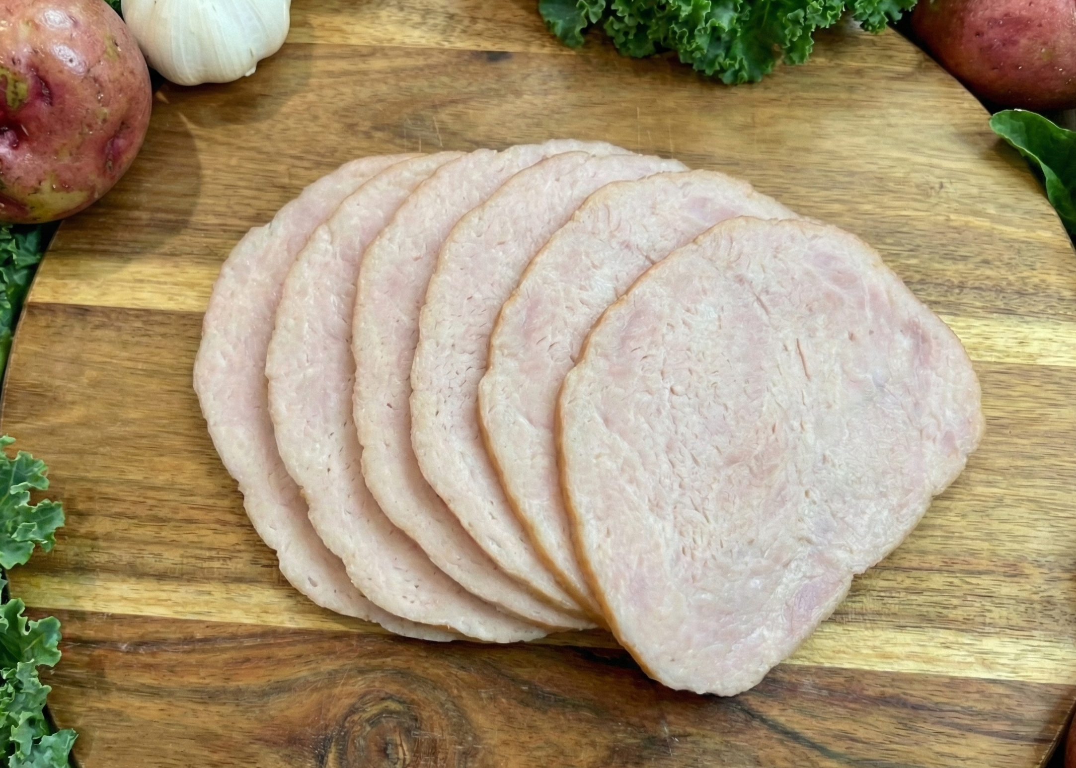 Sliced Smoked Canadian Bacon a wooden cutting board with vegetables around