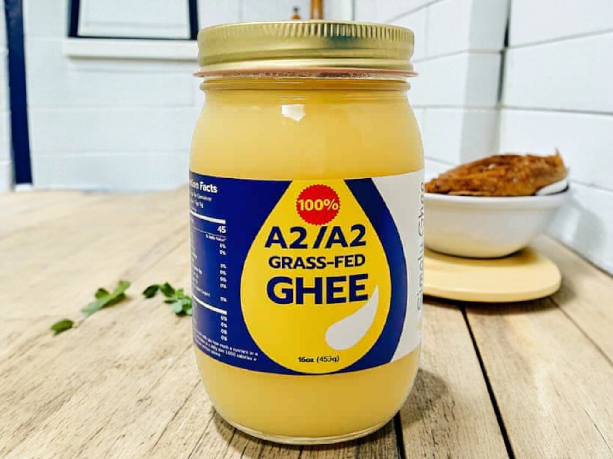 Jar of A2/A2 Grass-Fed Ghee on a wooden surface with a blurred background