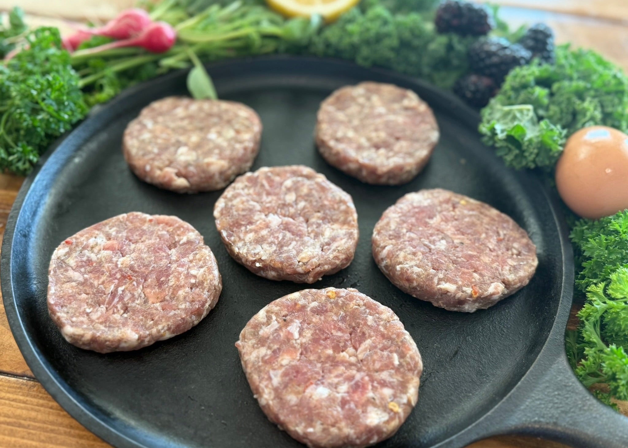 Raw sausage patties on a cast iron skillet 