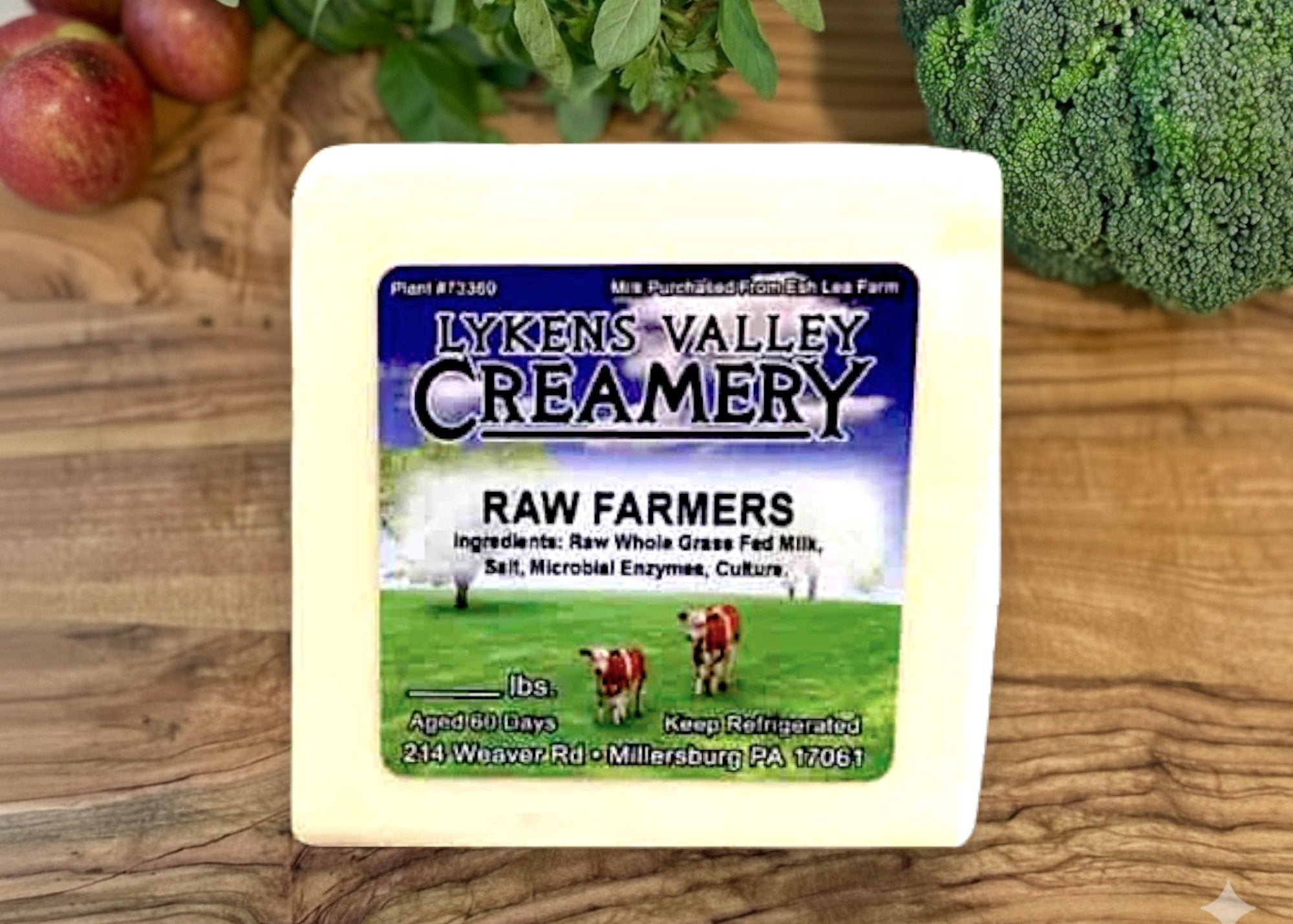 Cheese block with Lyken's Valley Creamery label on a wooden surface with vegetables.