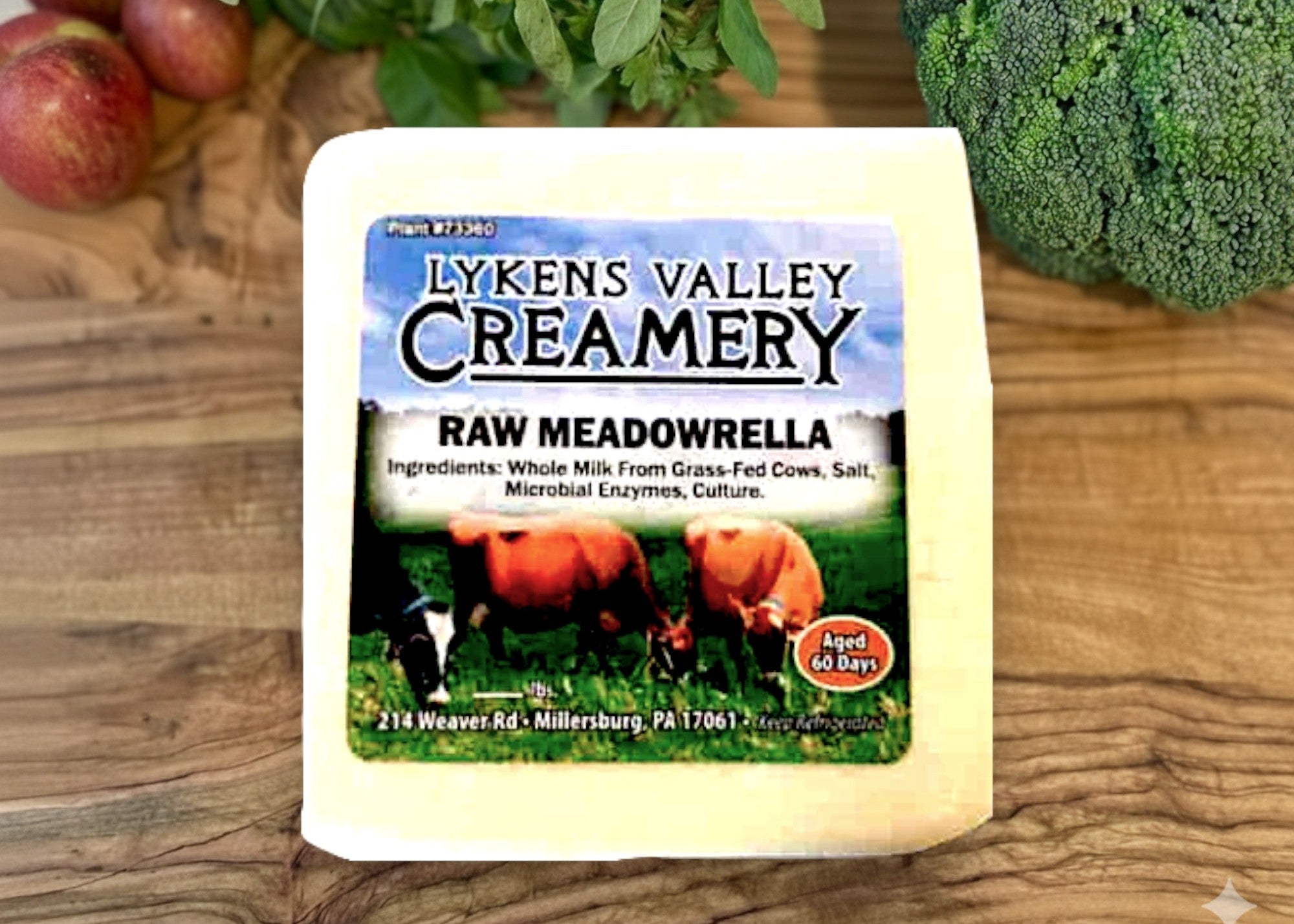 Raw Meadowrella from Lyken's Valley Creamery on a wooden surface with fruits and vegetables.